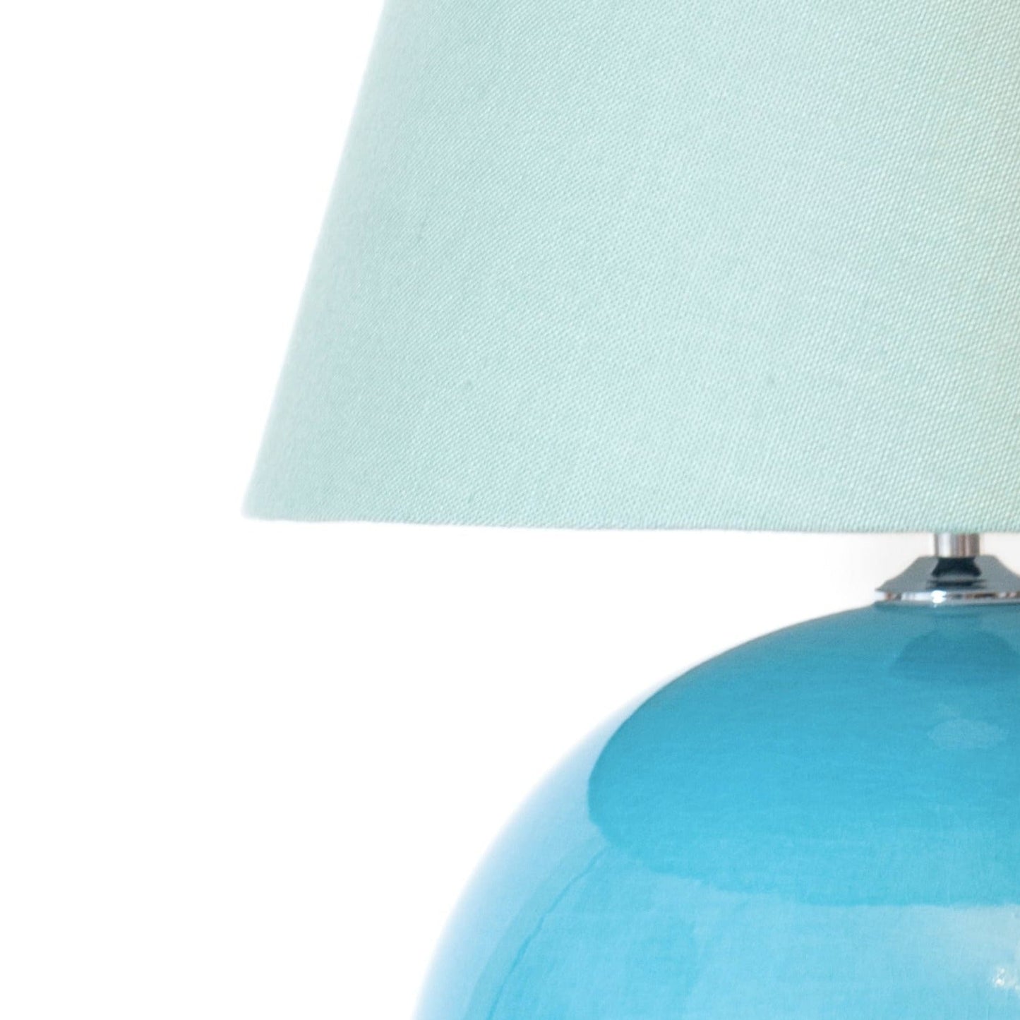 Turquoise ceramic lamp with a white lampshade on a white background